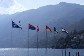 Flags waving at bay of Lake Lago Maggiore at village of Ascona, Canton Ticino, on a sunny summer day. Photo taken July 24th, 2022, Ascona, Switzerland.