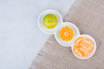 A white plates of peeled tangerines on sackcloth