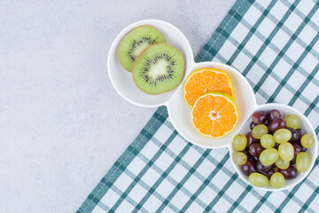 A white plates of fresh fruits on tablecloth