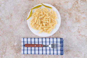 Simplistic dinner setup with macaroni and fork on a towel on marble background