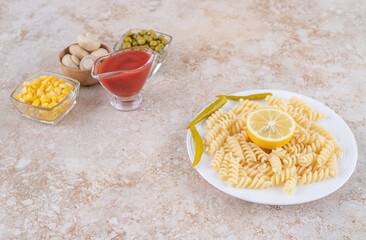 Small ketchup container and salad ingredients next to main course displayed on marble background