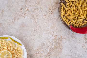 Oppositely aligned portions of pasta in raw and cooked states on marble background