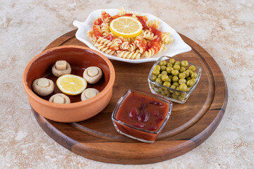 Appetizer ingredients with a platter of macaroni on marble background