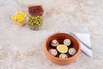 Toppings and dressing in bowls next to a portion of mushrooms on marble background