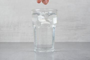 A glass of pure cold water on gray background
