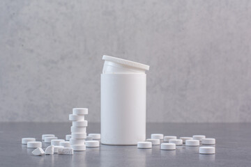 White medical pills and empty plastic container