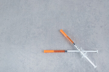 Two syringes with brown liquid on gray background