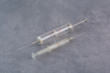 Two metal syringes on marble surface