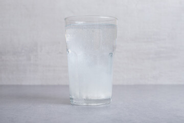 A glass of pure cold water on gray background