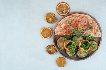 A wooden plate full of pita bread with sliced eggplant