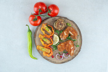 A wooden plate with peppers and tomatoes on white background