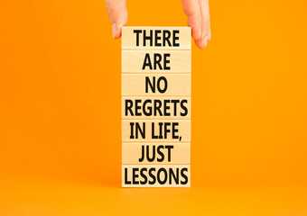 Regrets or lessons symbol. Concept words There are no regrets in life just lessons on wooden blocks on a beautiful orange background. Businessman hand. Business regrets or lessons concept. Copy space