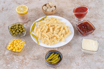 Delectable dinner set with main course surrounded with dressings and appetizers on marble background