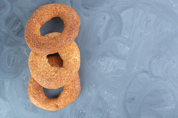 Three bagels coated with sesame lined up on marble background
