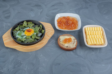 Chopped bean pulses with scrambled egg, butterbrot, butter slices and white cherry jam on marble background