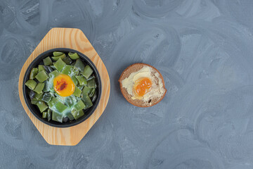 Butterbrot next to a small platter of chopped bean pulses with egg topping on marble background