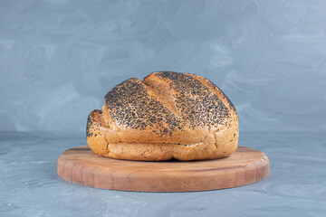 Black sesame seeds on a load of bread of a wooden board on marble background