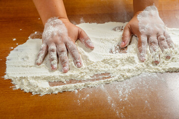 Hands of a Jewish woman on a wooden table in white wheat flour.