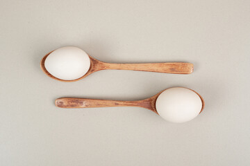 Two wooden spoons with chicken white eggs