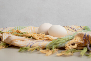 Two fresh chicken white eggs on tablecloth