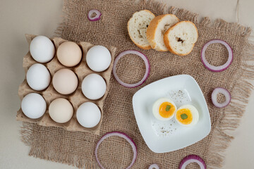 Boiled egg on white plate with fresh white bread on sackcloth