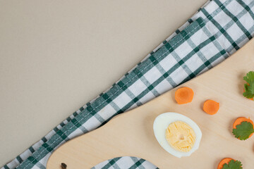 A wooden cutting board with sliced carrot and boiled egg