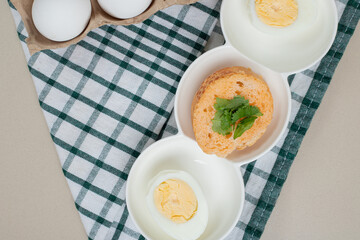 Fresh chicken white uncooked eggs with boiled egg on tablecloth