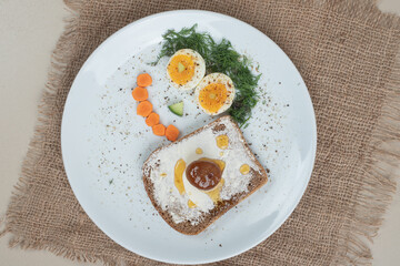 A white plate with toast and boiled eggs on sackcloth