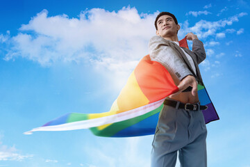 Lgbtq guy waving rainbow flag with proud face on over blue sky with clouds background, Human rights...