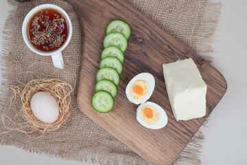 A cup of herbal tea with sliced cucumber and boiled egg