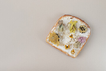 Toast with dried flowers and flour on gray background