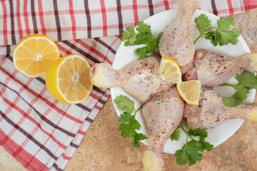 A white plate of chicken legs with sliced lemon