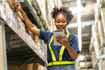 African American worker carries a tablet while counting inventories and checking the quality of...