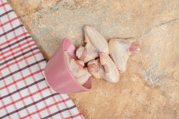 Unprepared chicken legs in pink plate on marble background