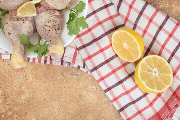 A white plate of chicken legs with sliced lemon