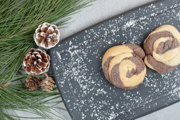 Sweet round cookies on dark board with pinecones