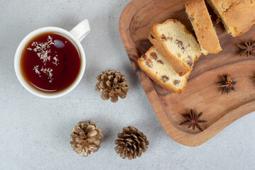 Delicious muffin with raisin and cup of tea on wooden board