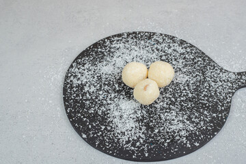 A dark cutting board with round pastry with powdered sugar