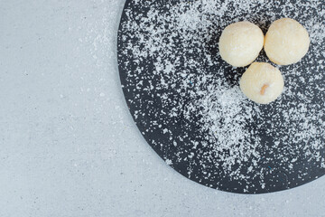 A dark cutting board with round pastry with powdered sugar