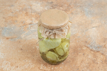 A jar of pickled vegetables on marble background
