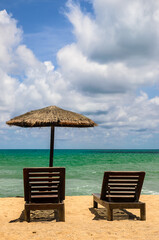 The beach chairs on sandy beach with cloudy blue sky and sun in the summer