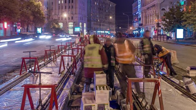 Tram rails at the stage of their installation and integration into concrete plates on the road night timelapse. Filling by liquid resin for reduction of vibration and noice. The process of