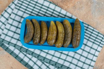 Pickled cucumbers on blue plate with tablecloth