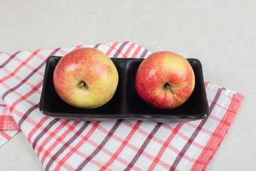 Whole red apples on black plate with tablecloth