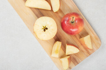 Whole and slices of red apple on wooden board