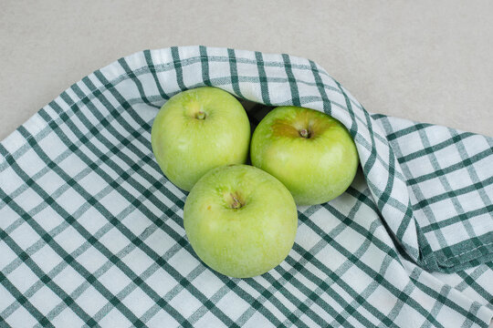 Whole green apples on striped tablecloth