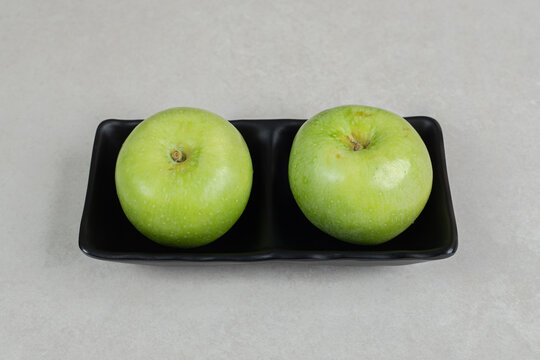 Fresh green apples on black plate