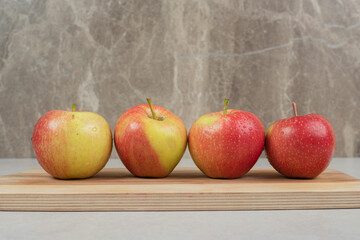 Whole red apples on wooden board