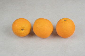 Three whole oranges on gray background