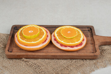 Fresh citrus fruit slices on wooden board